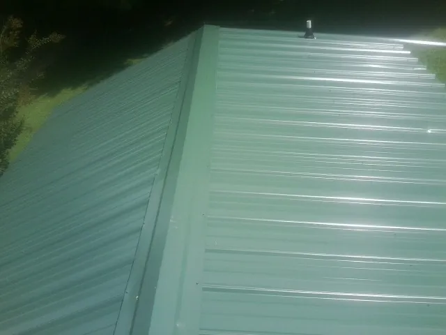 New green metal panels meeting at the ridge of a roof — Flat Roof Repair work by our crew in Beverly Hills