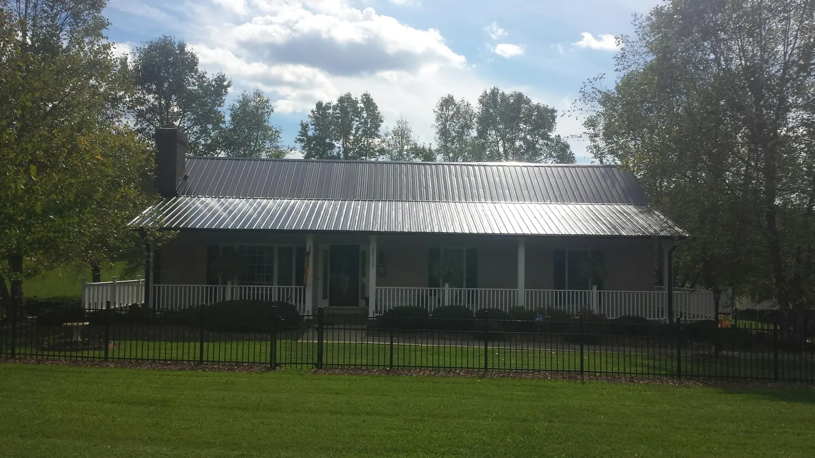 Gray metal roof on a brick ranch with a full width front porch — Gutter Guard Installation work by our crew in Beverly Hills